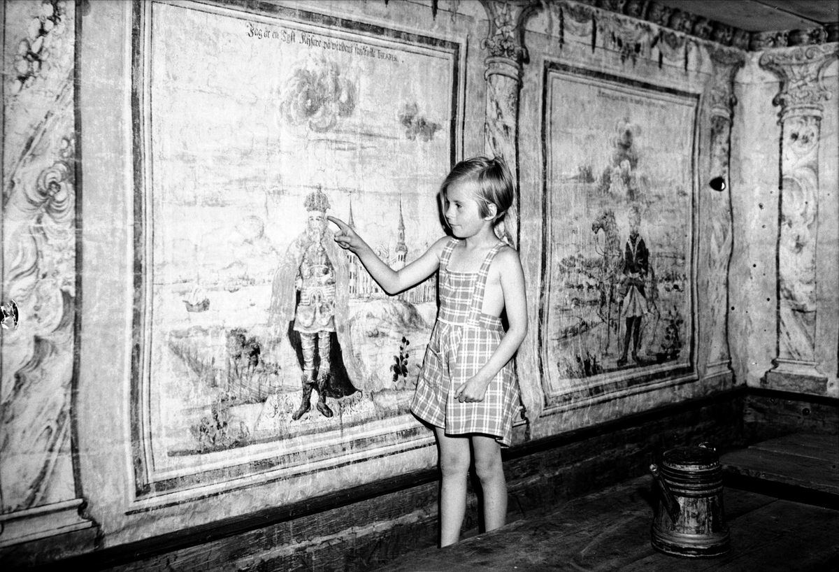 Flicka framför målning av allmogemålaren Hans Wikström i salen, Bärbystugan, friluftsmuseet Disagården, Gamla Uppsala 1952
