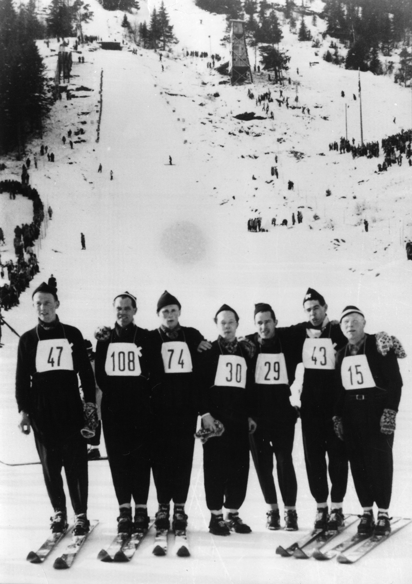 Kongsberghoppere under NM i Barvallen, Voss: John Kongsgård, Arne Ulland, Kåre Fulsebakke, Svein Lien, Ivar Nilsen, Ernst Knutsen, Arnholdt Kongsgård. Skijumpers form Kongsberg during the National Championship at Voss 1953.