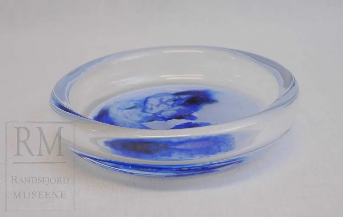 Rund skål i klart glass med ilagt hvitt og blått.