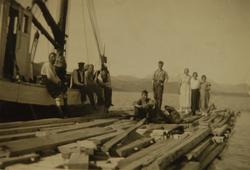 Mennesker med bygningsmateriale på en kai. MS Astrid ved kai