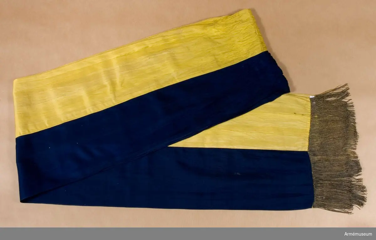Kravatten (fanbandet) är på längden hälften gul och hälften blå. I vardera kortändarna sitter en enkel guldfrans.