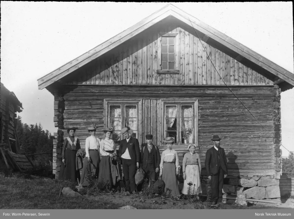 Menneskegruppe fotografert ved hytte