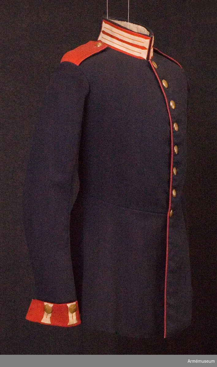 Grupp C.
Ur uniform för manskap, Landwehrsoffizier, Feldvebel, vid 2:a Gardesregementet, Preussen. Fastställt år 1843.
Av mörkblått kläde. Åtsittande med tvärsöm i midjan. Rocken är enradig med åtta knappar. På båda bakfickorna ett tvåuddigt lock med tre knappar. Axelklaffar av rött tyg, med mörkblått tyg under. Längd 14 cm och bredd 6 cm. Axelklaffarna är fastsydda vid ärmsömmarna och fästade vid rocken med knappar. Nr "1" kompaninummer. Foder av grov linne- lärft på övre delen. Nedre delens foder är av svart grovt satängtyg. Knapparna är gjorda av koppar, 2 cm i diameter. På bröstet, på fickorna och ärmuppslagen knappar av större format, på axlarna knappar av mindre format med kompaninummer. Kragen är upprättstående med raka vinklar av rött tyg med blå passpoal på kragens överkant. Kragen har har på båda sidor två knapphål -1 cm breda- av bomullsband- -beteckning för gardesregemente- samt tre hyskor och hakar. Kragen är fodrad med mörkblått tyg. Röda passpoaler längs rockens främre kant och de bakre fickorna lock. Ärmuppslag -svensk modell- rakskurna av rött tyg 6 cm  höga med två knapphål av vita bomullsband, 5,5 cm långa och 2 cm breda.
LITT  Uniformenkunde, R. Knötel. album. Preussen. Uniform för 2:a Gardesregementet till fots år 1843. Färgbild. Geschichte der Bekliedung und Ausrüstning der königlichen Preussischen Armée in den jahren 1808 bis 1878, Berlin. Sid 3 paragraf 572. Vapenrocken (m/1843) infördes oktober 1842. Das Deutsche Reichsheer. G.Krickel. Sid 11. Det 2:a Gardesregementet till  fots fick svenska ärmuppslag i stället för brandenburgska enligt dagorder av den 18 januari 1834. Uniformenkunde das Deutsche Heer. R.Knötel IV:e textvolym. sid 28. Regementet grundades år 1813.
Vapenrocken har en pappersetikett, där det står: "Vapenrock, Preussisk modell. Avlämnad år 1845 till kungl. krigs-Collegium av överst-leut. Söderberg".