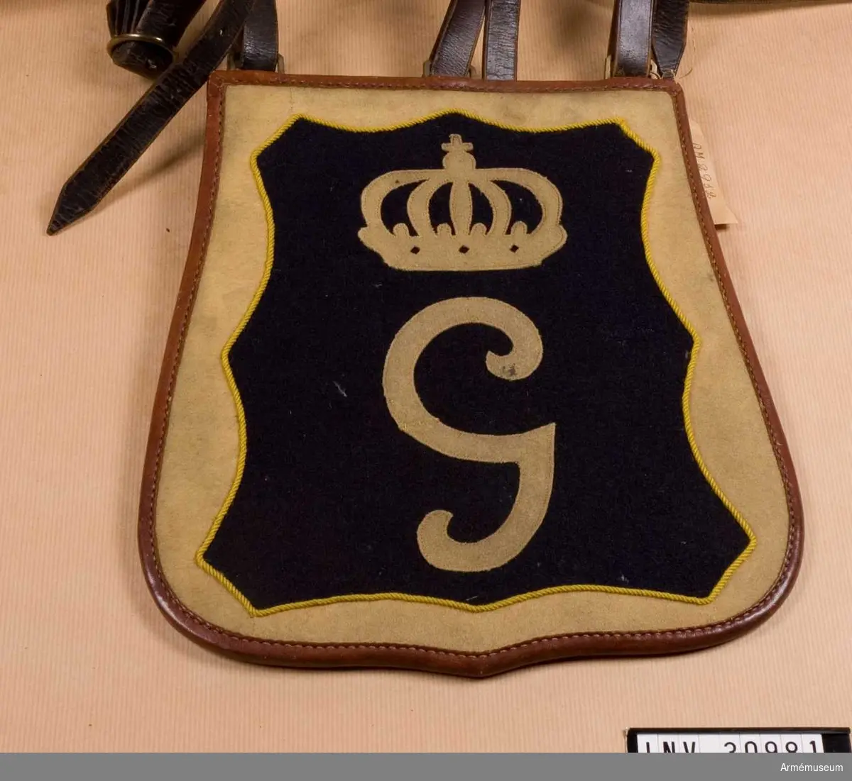 Sabeltaska av läder med blått och gult kommisskläde på locket. Gustav III:s monogram under en kunglig krona.