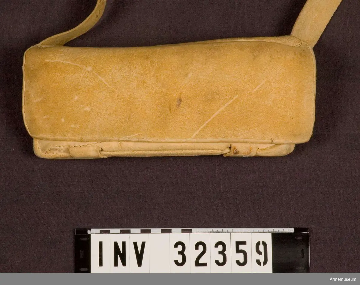 Patronväska av gult, sämskat läder med en bleckplåtsinsats med rum för 12 patroner med 18 mm kaliber.