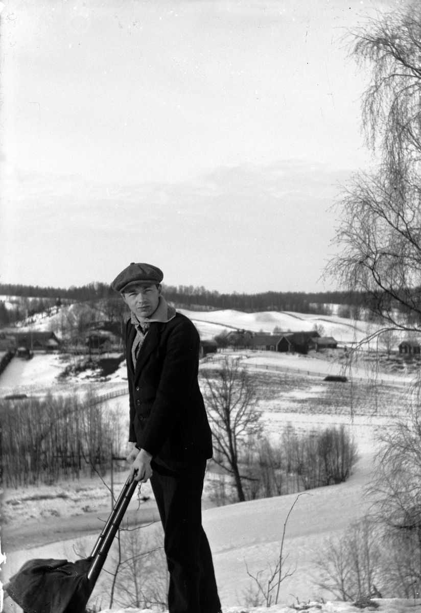 Gustav Andersson med sparkstötting, i bakgrunden ett snöigt landskap med spridd bebyggelse.