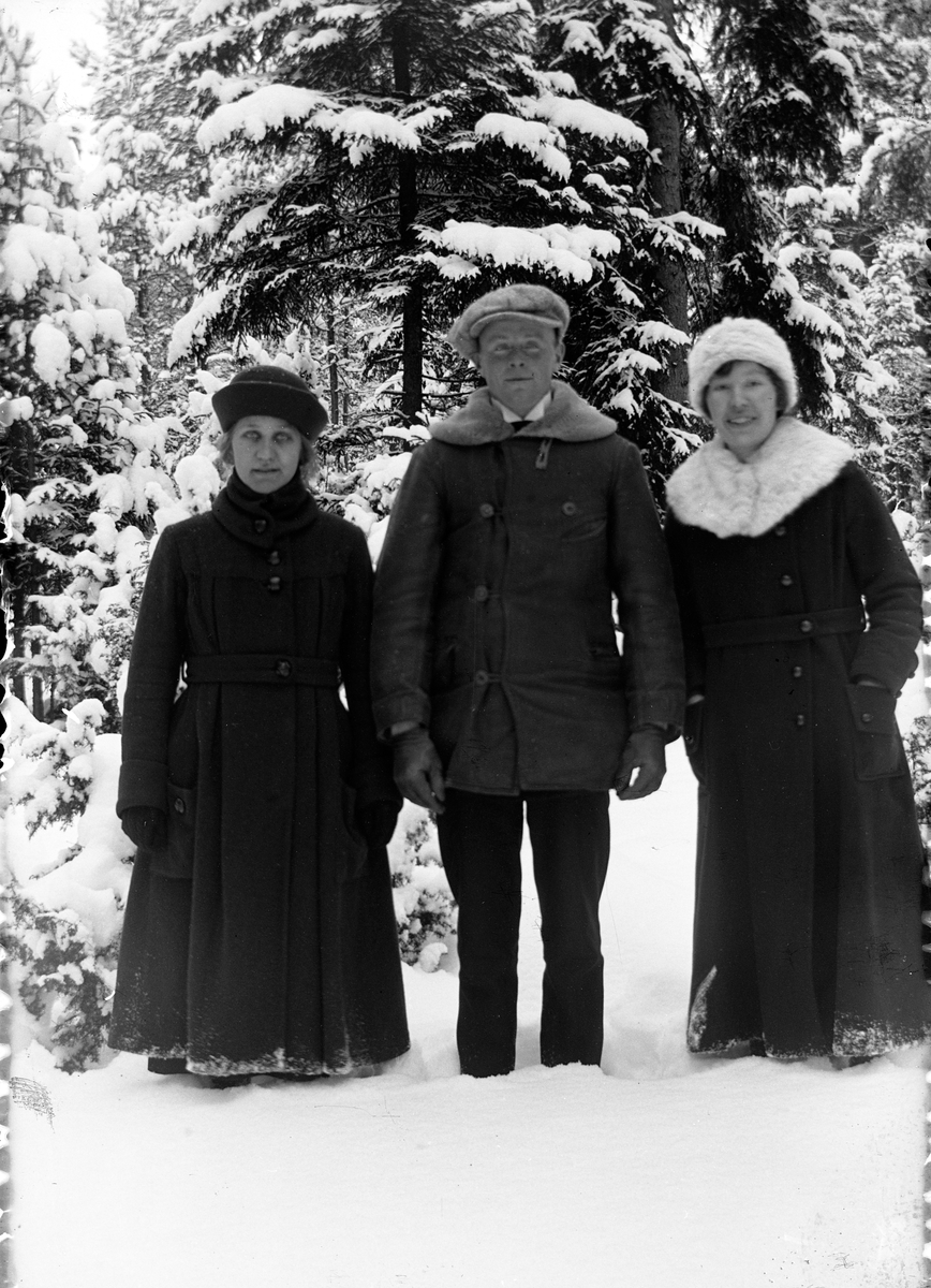 En man flankerad av två kvinnor, står i en snöig barrskog vid Lungkliniken i Eksjö.