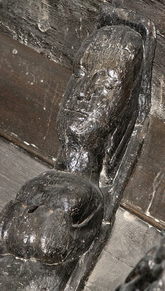 Nereid iförd en turbanliknande huvudbonad med stora plymer. Bålen är naken och armarna är ersatta av enkla bladslingor med upprullat ändparti. Övergången från överkropp till underkropp markeras av stora bladflikar. Skulpturens fiskstjärt slingrar sig kring stjärten till en fisk eller delfin, vars huvud är synligt vid skulpturens fotända.

Skulpturen är svagt frontalsvängd och upptill utdragen i en spetsig vinkel. Baksidan är tvåsidig, utom det översta partiet, samt försedd med flera större urtag. Bakstycket är kraftigt och snidat i ett med skulpturen.
Skulpturen är relativt välbevarad.

Text in English: Nereid wearing a turban-like head-dress with large plumes. The trunk is nude and the arms are replaced by insignificant leafy vines with the ends rolled up. The transition to the tail section is marked by large leafy ornamentation. The fish tail is entwined with the tail of a fish or dolphin whose head can be seen at the foot of the sculpture.

The sculpture is curved slightly to the front and at the top comes to an angled point. The rear side is double-sided, except for the upper section, and has a number of hollowed-out areas or indentations. The backboard is robust and carved in one piece with the figure.
The sculpture is rather well preserved.