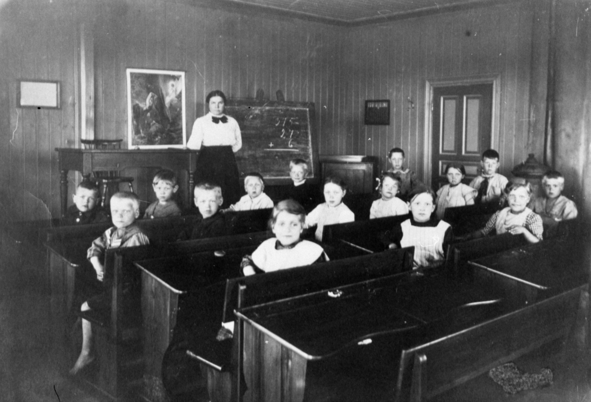 Flickor och pojkar sittande i skolbänkar i Rantorpsskolan i Lindome. Fröken stående vid katedern.