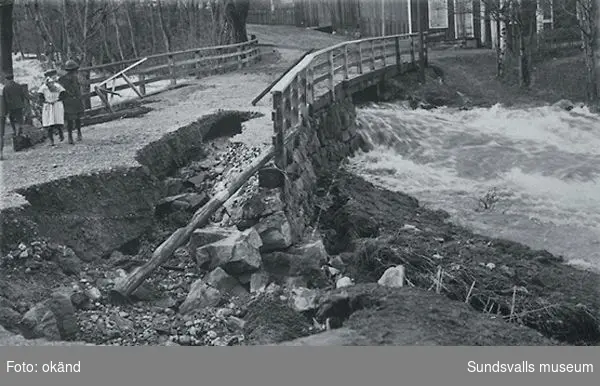 Gamla bron över Sidsjöbäcken uppe vid Fagerdal i närheten av fröknarna Löfgrens speceriaffär. Kortet taget vid översvämningen 1919.  På bild tre barn.