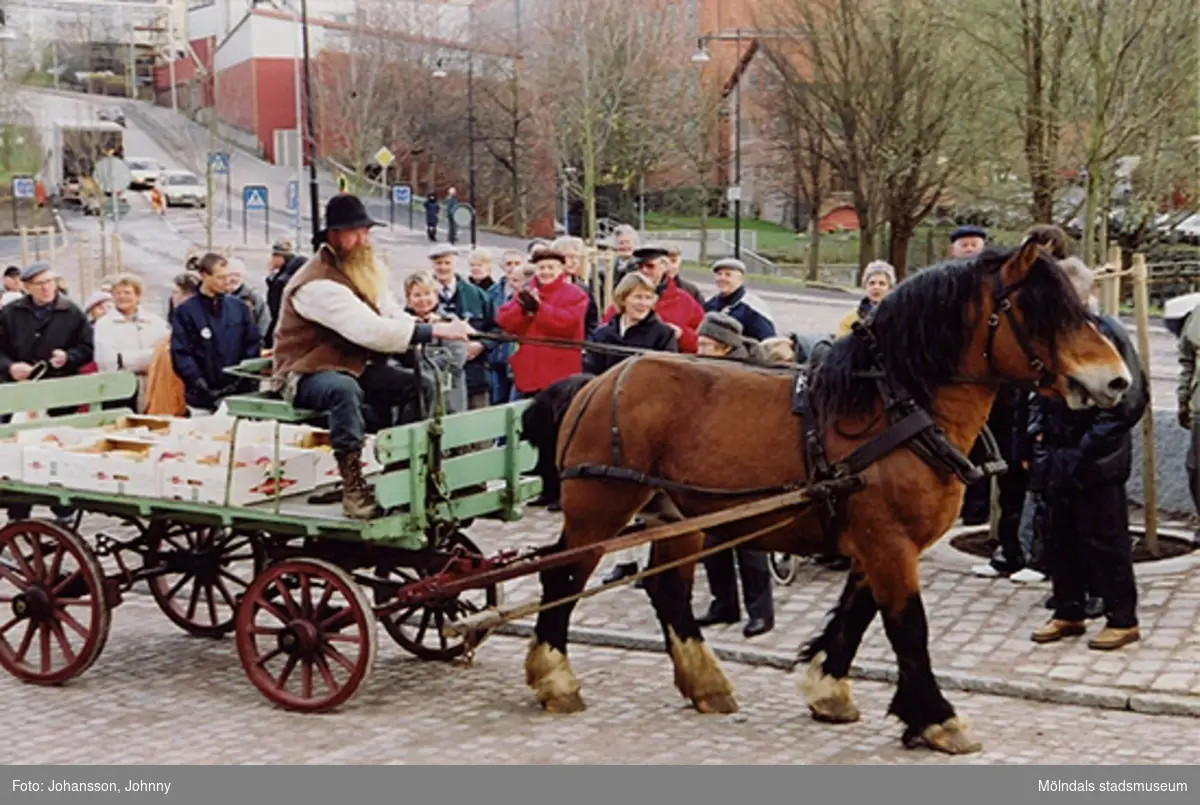 Gamla torget i Mölndal den 22:a november 2001. Folk tittar på när en kusk med häst och vagn åker genom torget.
Invigning efter omläggning och stenläggning av torget.