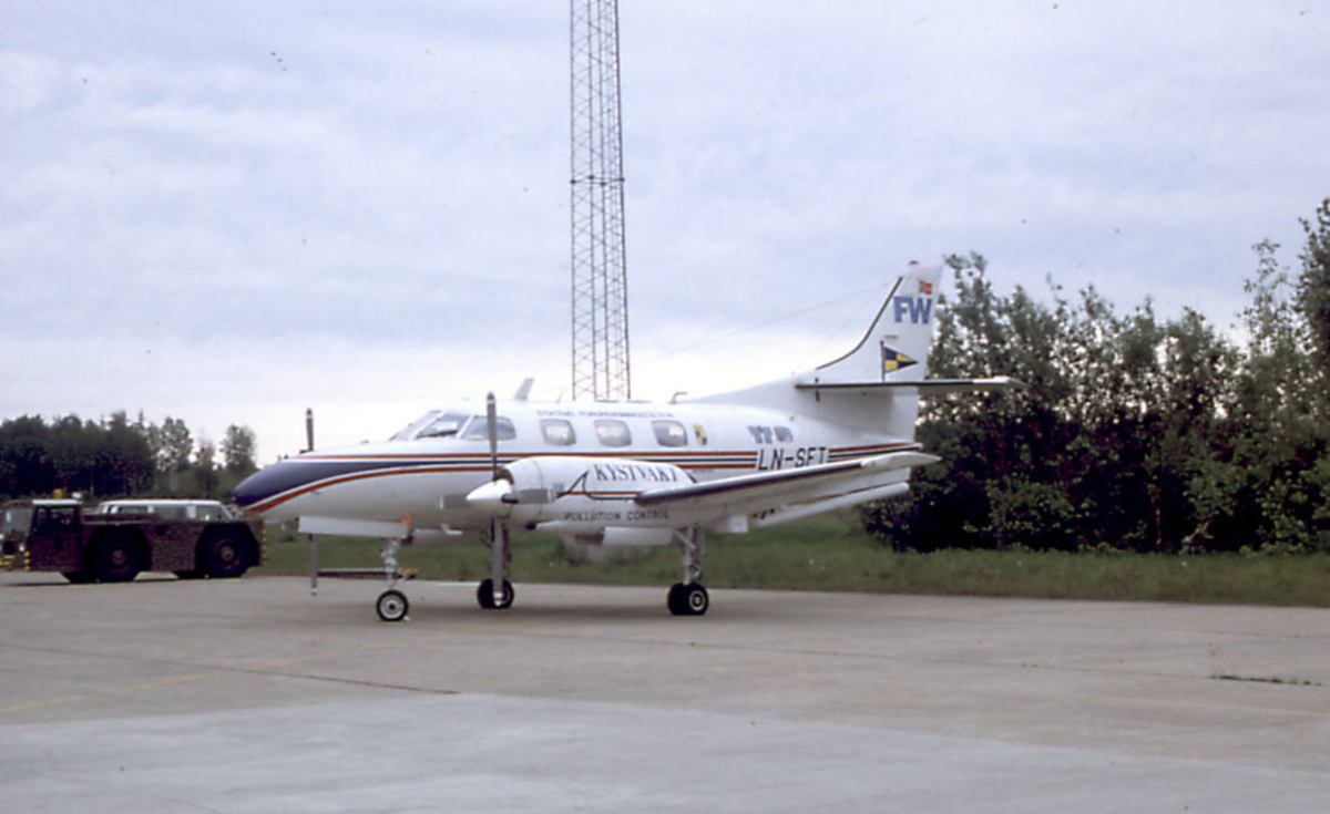Lufthavn, ett fly på bakken Fairchild Aircraft Corporation SA226-T(B) FW LN-SFT fra Kystvakten. to kjøretøyer i bakgrunnen.