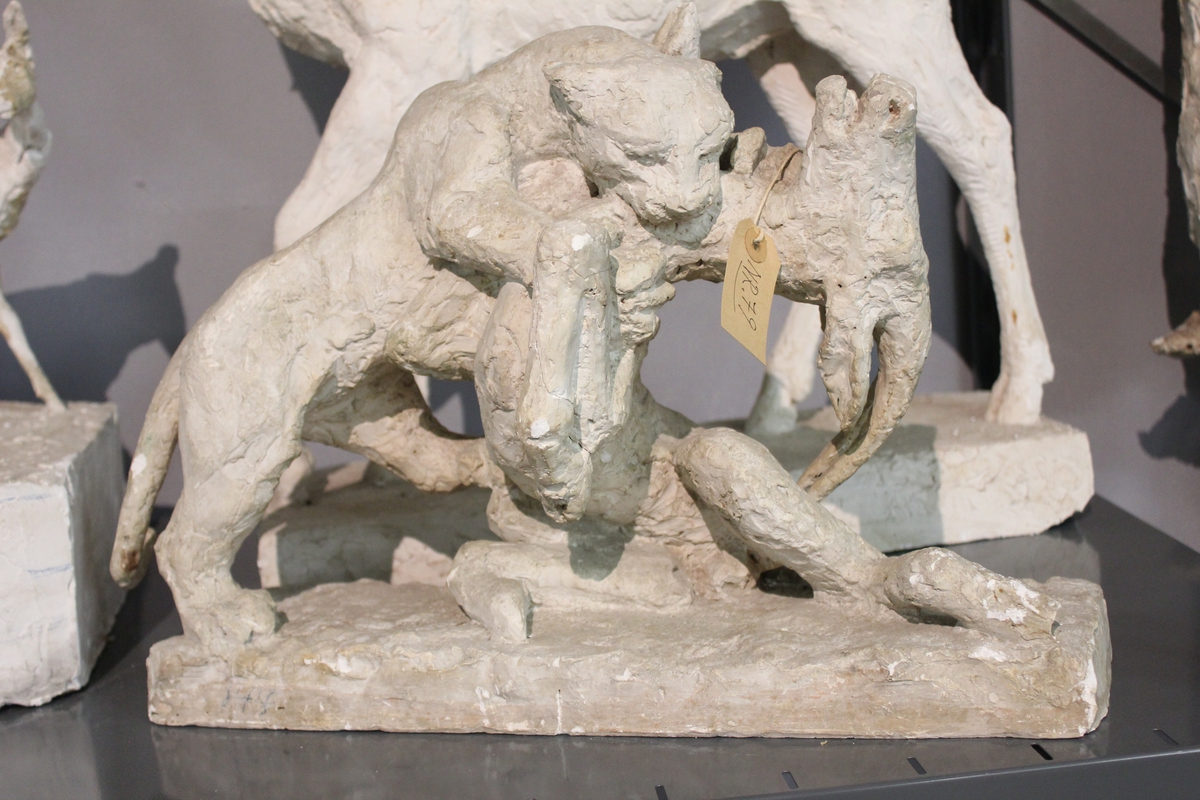 Skulptur i gips av et kattedyr som avliver et hjortedyr. Tittel: "ROVDYR" fra 1933.