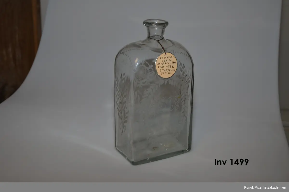 Flaska för brännvin av glas med årtalet 1824  ingraverad.  Ornerad med blom- o. bladrankor på alla sidor.  Bokstäverna  A: G: L: B: ingraverade  på frontsidan.

 fr.Nyby, Stafbv sn. Uppland