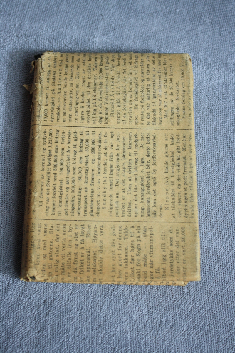 Bok pakka inn i avispapir. Avia er frå ei utgåve av Bergens Tidene frå ons. 4. juni 1930.