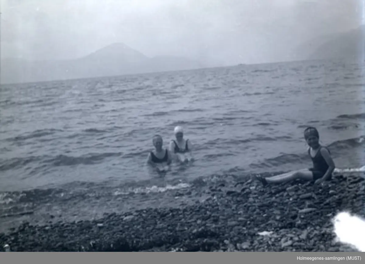 Tre kvinner med badehette og badedrakt bader i sjø med små bølger (bare hode og skuldre stikker opp av vannet). Muligens samme sted og tidspunkt som ST.K.HE 2007-011-0056 og -0057.