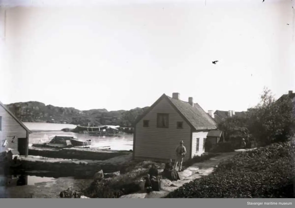 Ydstebøhavn på Kvitsøy sett mot sørøst fra Lauritz Haalands hage. Personene på bildet er ukjente. Ytters til venstre i bildet ses deler av sjøhuset som tilhørte Toldus Nøstvold (nyere enn på ST.S 1983/57:78), huset midt i bildet tilhørte også Nøstvold.