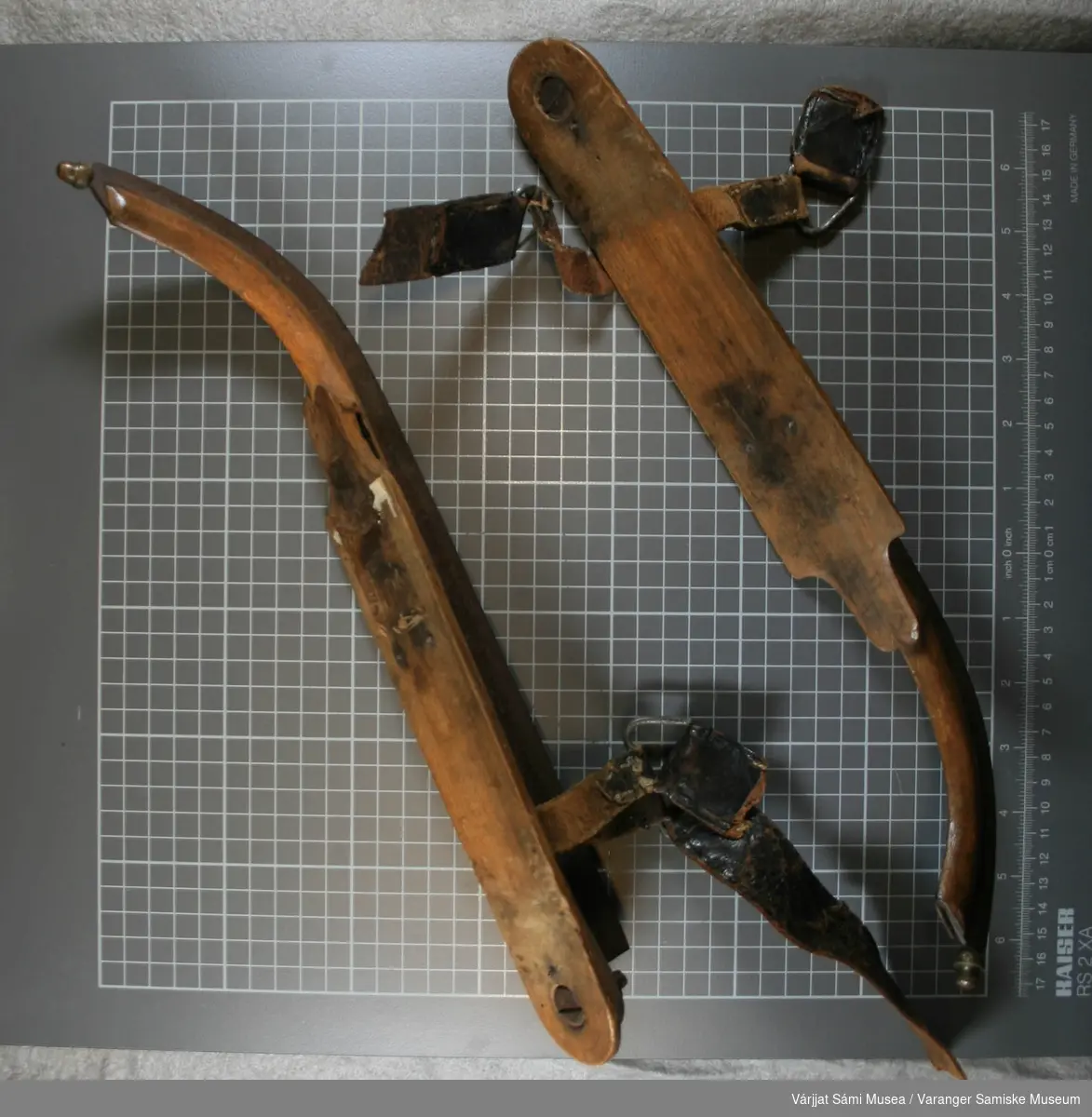 Ett par dameskøyter som er laget av tre og stål. På skøyterne er det reimer som er laget av skinn og metall. Den er bøyd i tuppen.