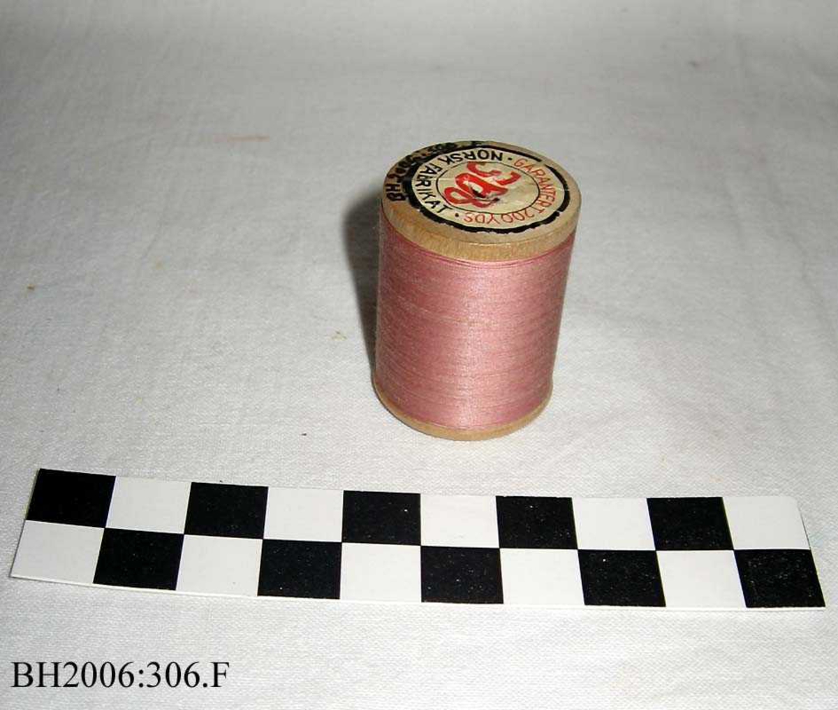 Trådsnelle med rosa tråd, og kjerne av tre og etikett i hver ende.
