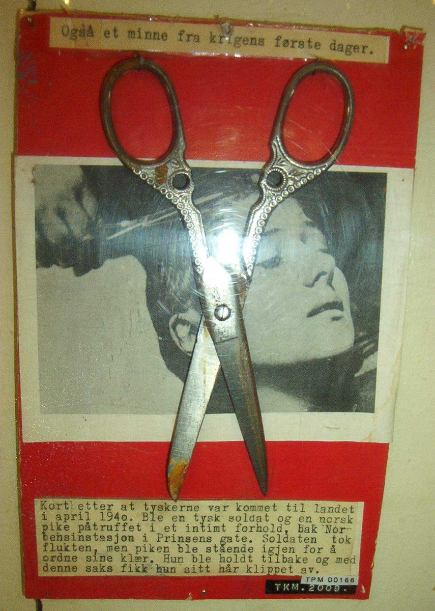 Metallsaks montert på kartong med tekst og illustrasjonsfoto. (Fotoet er hentet fra spillefilmen "The Passion of Joan of Arc" fra 1928)