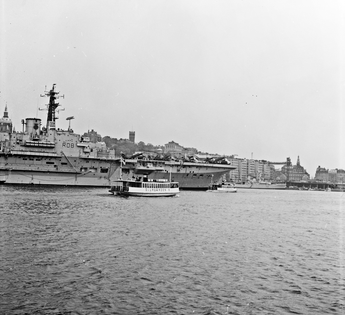 DJURGÅRDEN 5 och DJURGÅRDEN 6 på Stockholms ström. I bakgrunden: hangarfartyget HMS BULWARK (R08), fregatten HMS ANDROMEDA (F57).