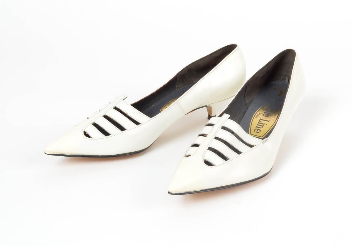 Ett par høyhælte sko med pose og eske. Str. 4,5.
Modell 5075. Solgt for våren 1964 - 9573 par.