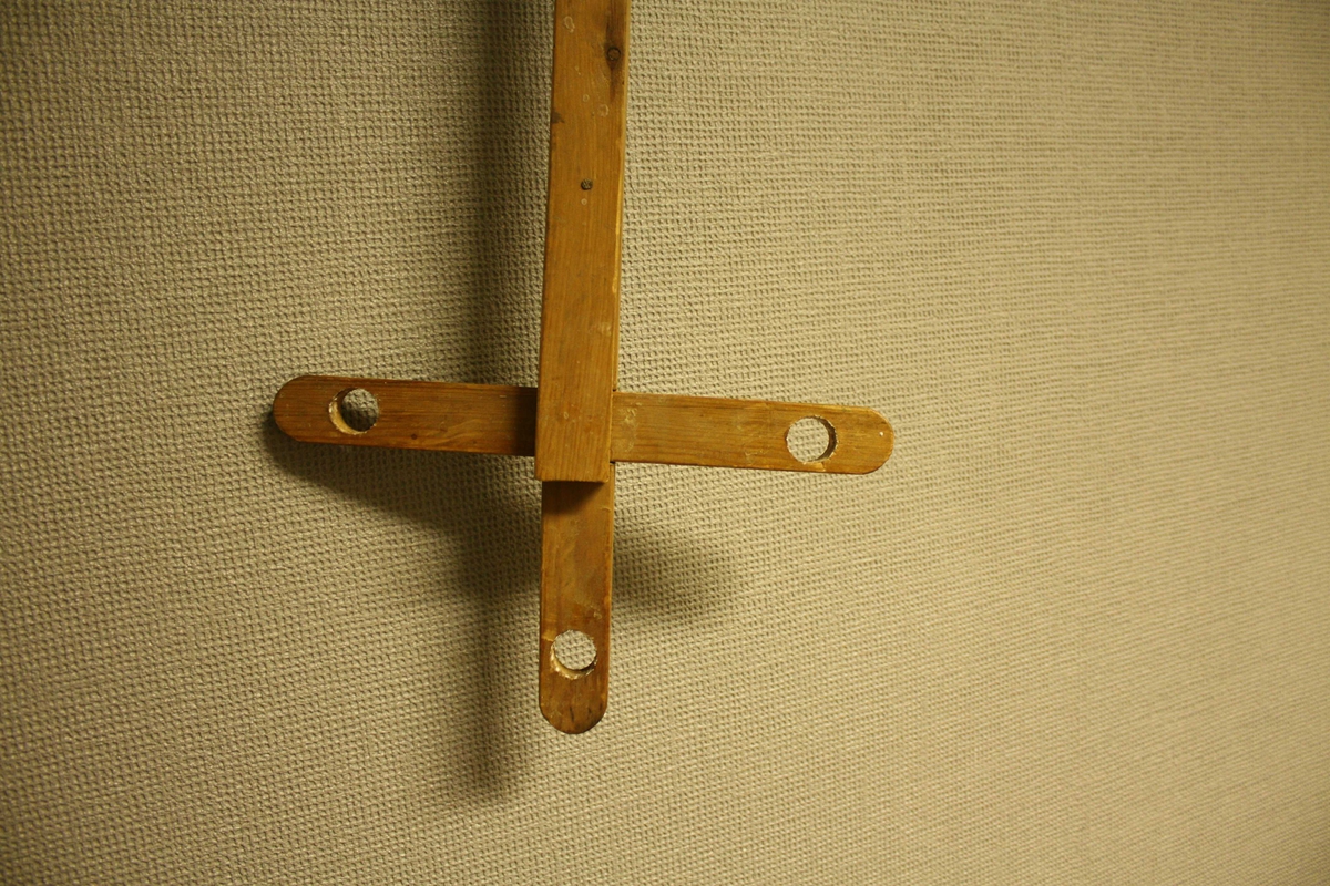 Langt, utrekkbart stag, formet som et kors i endene hvor det er boret tre gjennomgående hull for stearinlys.