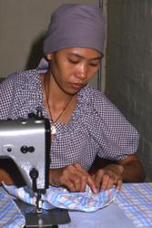 Kvinnelig båtflyktning arbeider ved symaskin i Tuen Mun flyk
