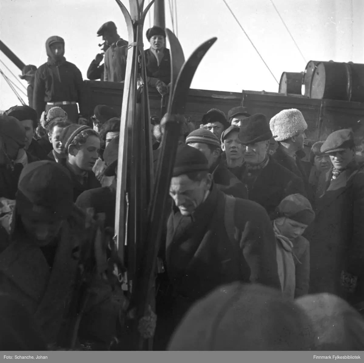 Fra kretsrennet i Vadsø 1946. Olav Odden ankommer Vadsø for å delta. Vi ser han midt på bildet, bak noen skipar. Det er flere på bildet. De er kledt i luer og skjerf.