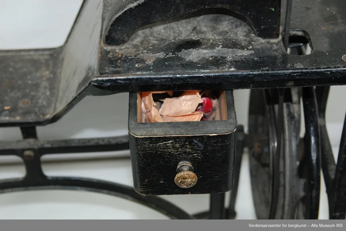 Symaskin med pedal.
Hele rammen til symaskinen er i metall.
Maskinen har en liten skuff.