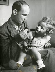 Mann med barn på fanget. Mannen har en pipe i munnen og barn