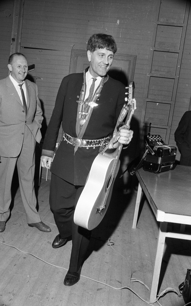 Natt 702, 12 juni 1967

Bild på Jokkmokks-Jokke när han står i ett rum. Han bär samedräkt med samebälte runt livet samt bär en gitarr i handen. En annan man klädd i kostym står bakom honom. Ett dragspel står på ett bord till höger.