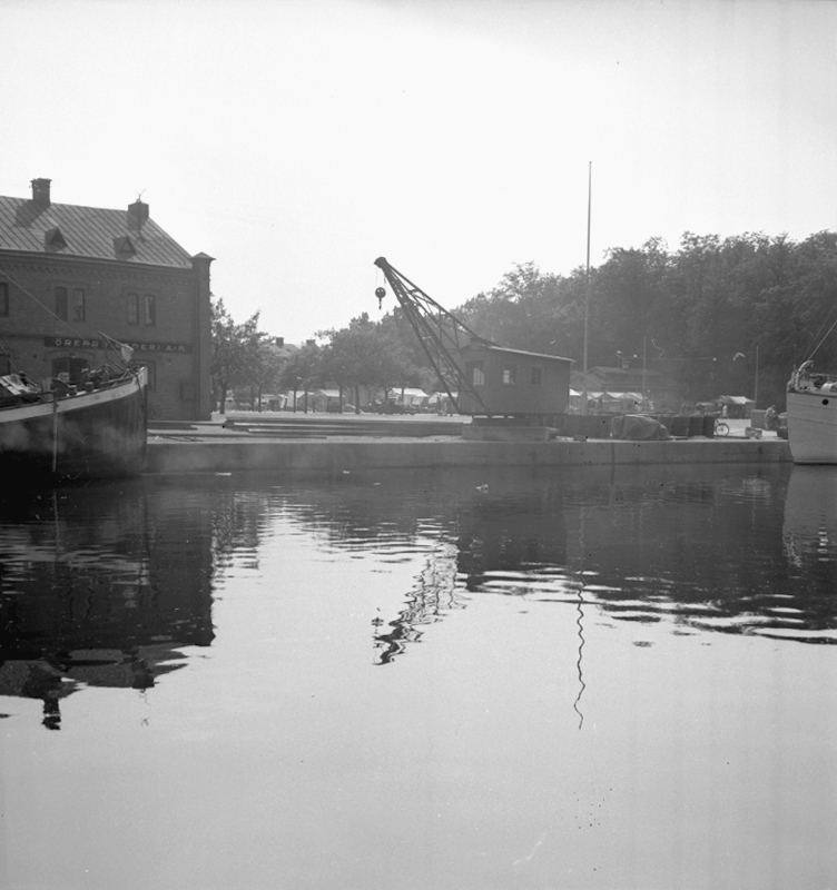 Motiv från Örebro, Svartån och byggnader.
Hamnplatsen Örebro Rederi ABs hamnmagasin, till vänster  i bakgrunden den gamla saluhallen.

15 juli 1939.
