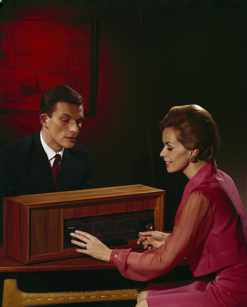 Reklamefoto av en mann og en kvinne rundt et Radionette radioapparat....