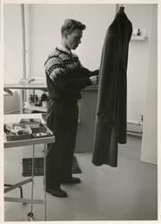 Mann arbeider utfører detasjering (flekkfjerning) på frakk v