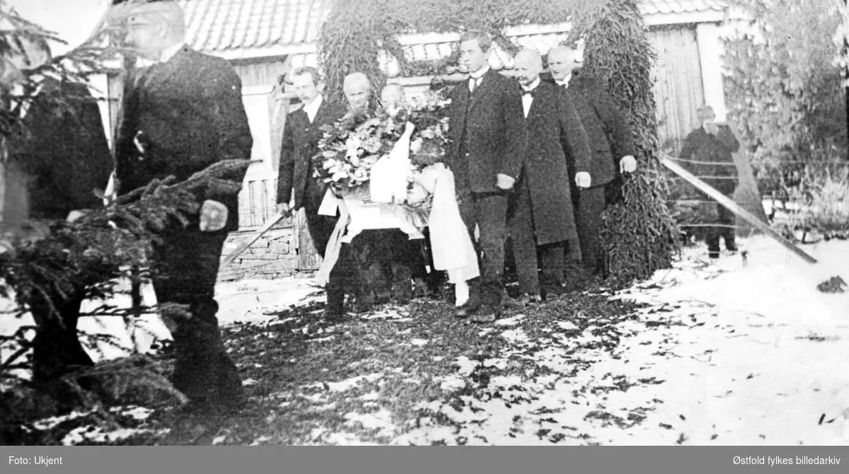 Begravelse på gården Krosby i Rødenes, Marker ca. 1910 ?. Ingen navn.
Kista bæres fra hovedhuset og ned til hest og slede. Begarvelsesportal med kors i granbar, og veien fra huset med til hovedhuset er strødd med granbar.
I bakgrunnen en mann, en av de sørgende som snyter seg med lommetørkle.