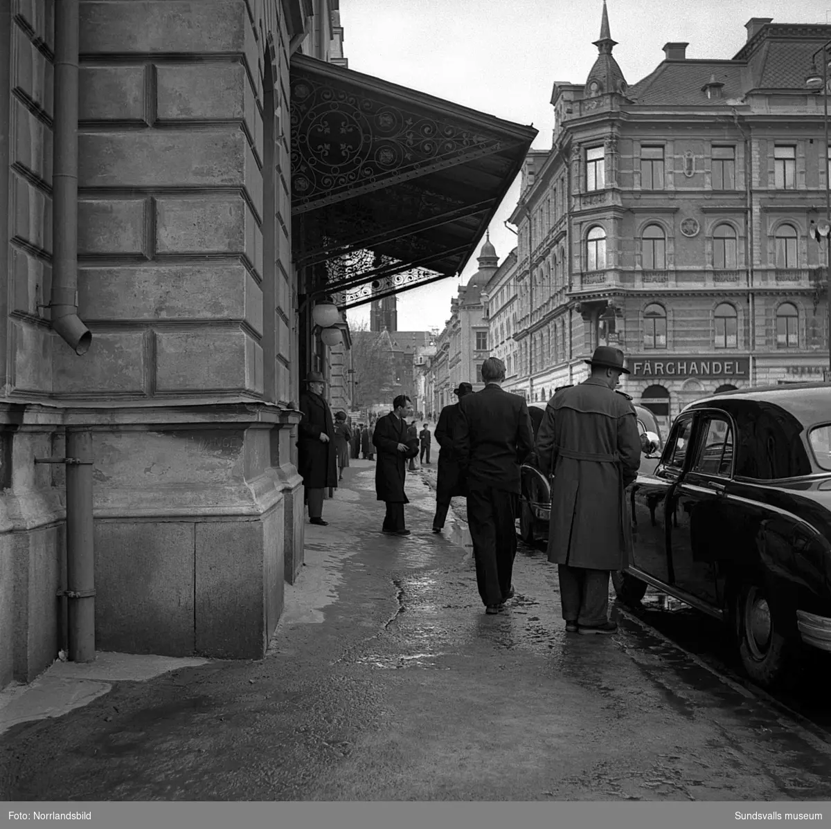 Utanför Stadshusets entré plockar en man med kartonger i bakluckan till en bil. I bakgrunden syns Hirschska huset.