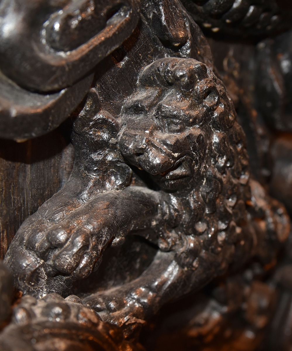 Skulpterad sköld med upprätt, mot höger gående lejon. Lejonet är snidat i hög relief, med heraldiskt stiliserad hållning. Sköldens kontur är rokokomässig, med kanter av varierande bredd och rik pärlbroskdekoration. Upptill avslutas skölden med en ellipsformad broskvolut. Sköldens baksida är slät.

Text in English: Shield with upright, rightward-facing lion. The lion is carved in high relief and reproduced in perspective. It is seen in profile, and its posture is heraldically stylised. The shield has an almost rococo-like outline, with edges of varying width and rich earshell work decorations.The top is finished with an ellipse-shaped pearlwork scroll. The reverse side of the shield is smooth.