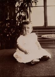 En baby (trolig Erica Mathiesen) sitter på et teppe på en gl