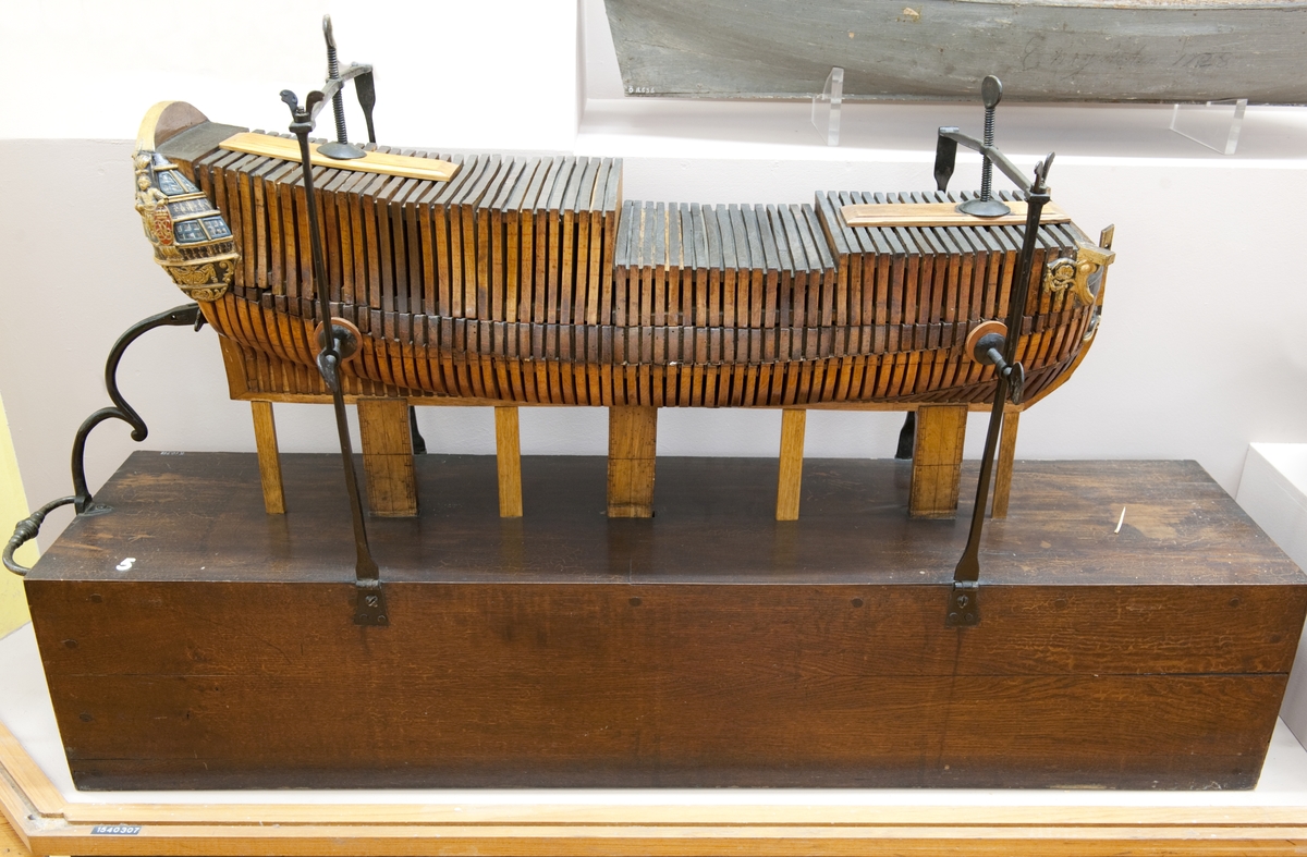 Sektionsmodell av ett linjeskepp från 1738
Modellen består av olika sektioner som sammanhålles av 2 st "skruvtvingar" fasta till en träsockel i form av en låda med järnhandtag. Modellen vilar å 3 st stöd med tumskala. Sockeln (lådan) mäter 1350X296X269 mm.