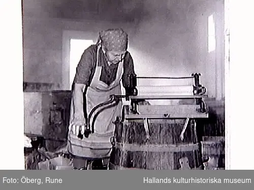 Klädvård. Tvättning av kläder i gårdens brygghus. Tvätten kokades i en stor gryta och tvättades i den handdrivna tvättmaskinen i förgrunden. Först kokades vittvätten, sist skurades trasmattorna. El-driven tvättmaskin köptes på slutet av 1950-talet. På bild 9-10 manglar Maria.