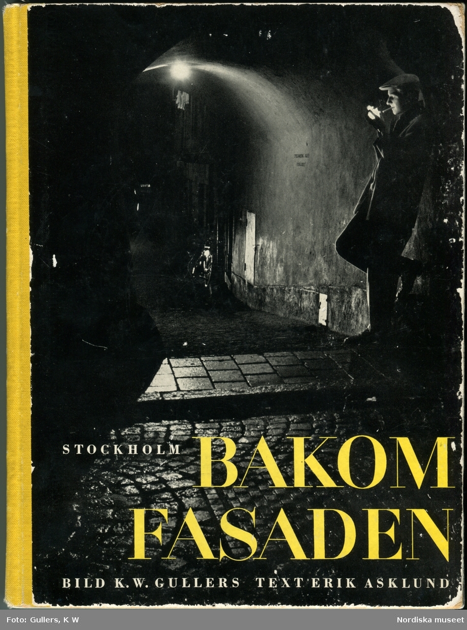 Nattstämning vid Bredgränd i Gamla Stan, Stockholm. En man står i upplyst valv och tänder en cigarett. 