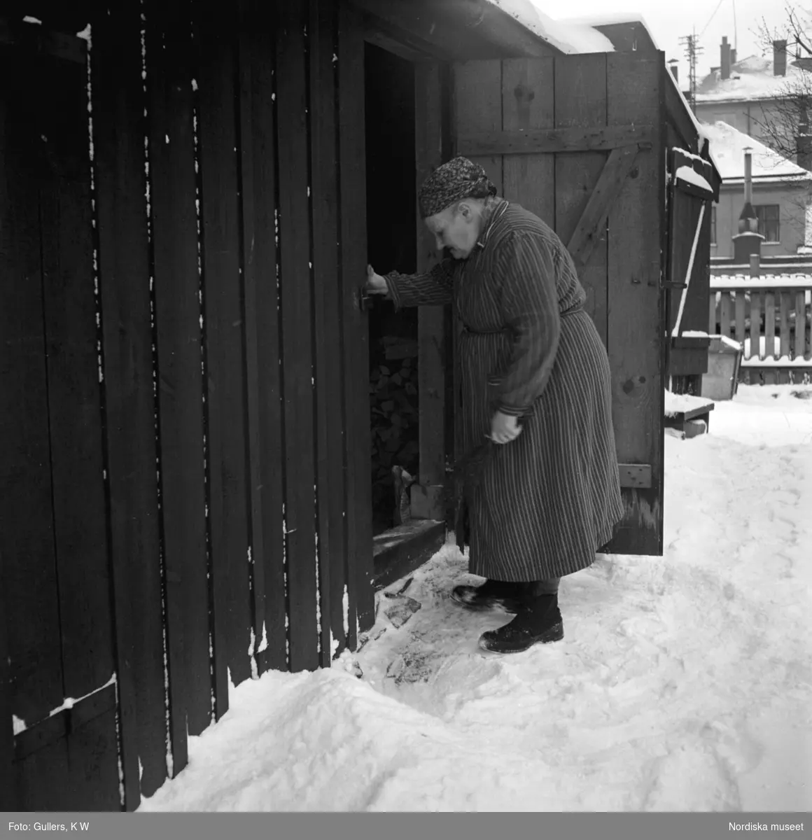 "En gammal kvinna har mödosamt skottat en smal gång från sin dörr efter nattens snöfall." Högalid, Södermalm, Stockholm.