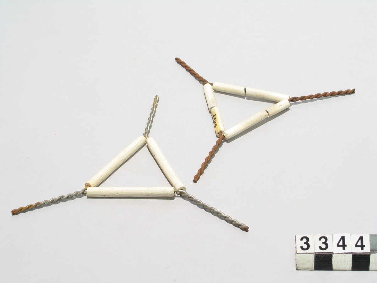 Två st. trianglar av tvinnad järntråd med skyddsrör av oglaserat porslin.