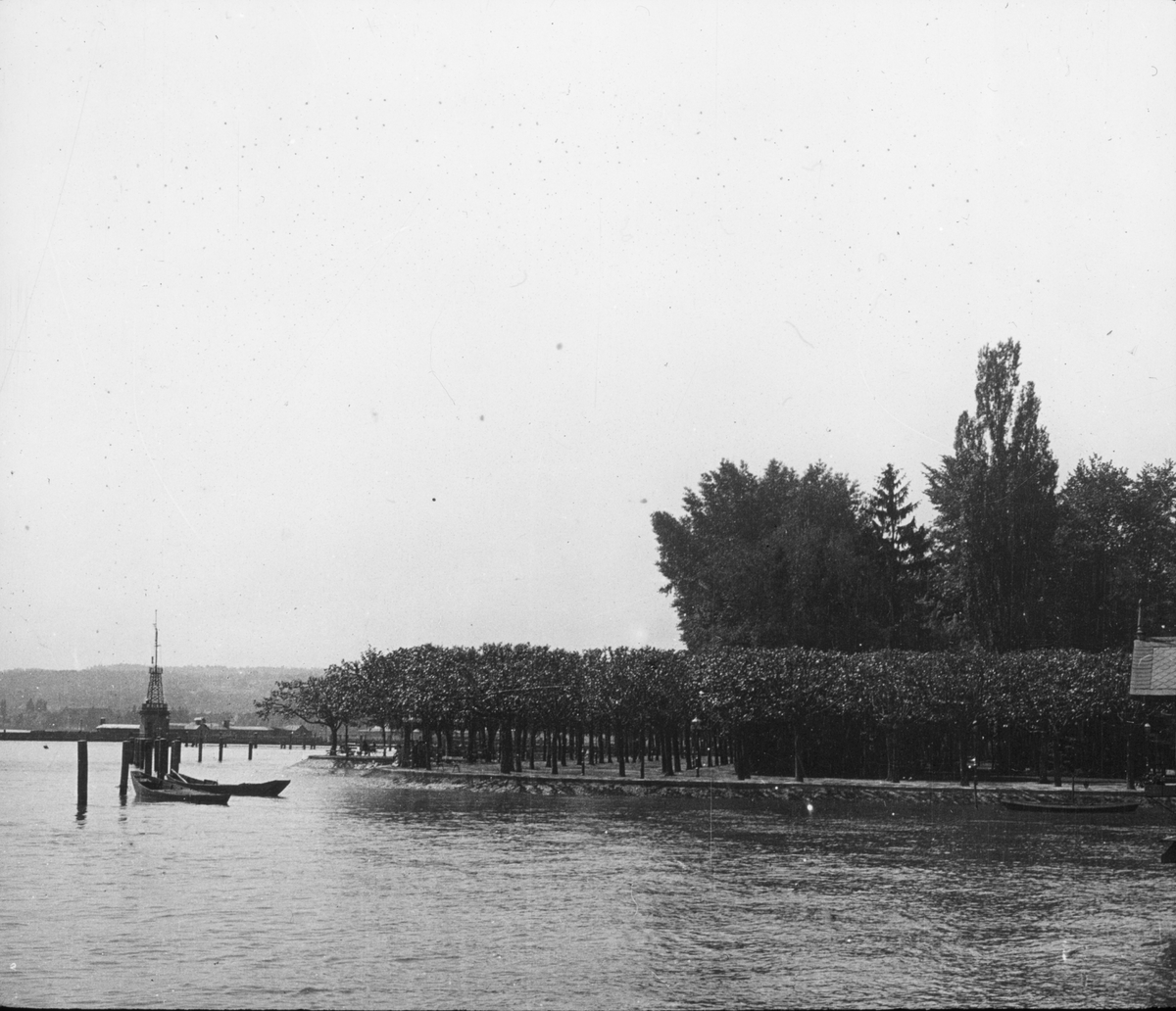 Skioptikonbild med motiv av strandpormenad vid kanten av Bodensjön.
Bilden har förvarats i kartong märkt: Resan 1906. Arlberg- banan 2. Konstanz 6.