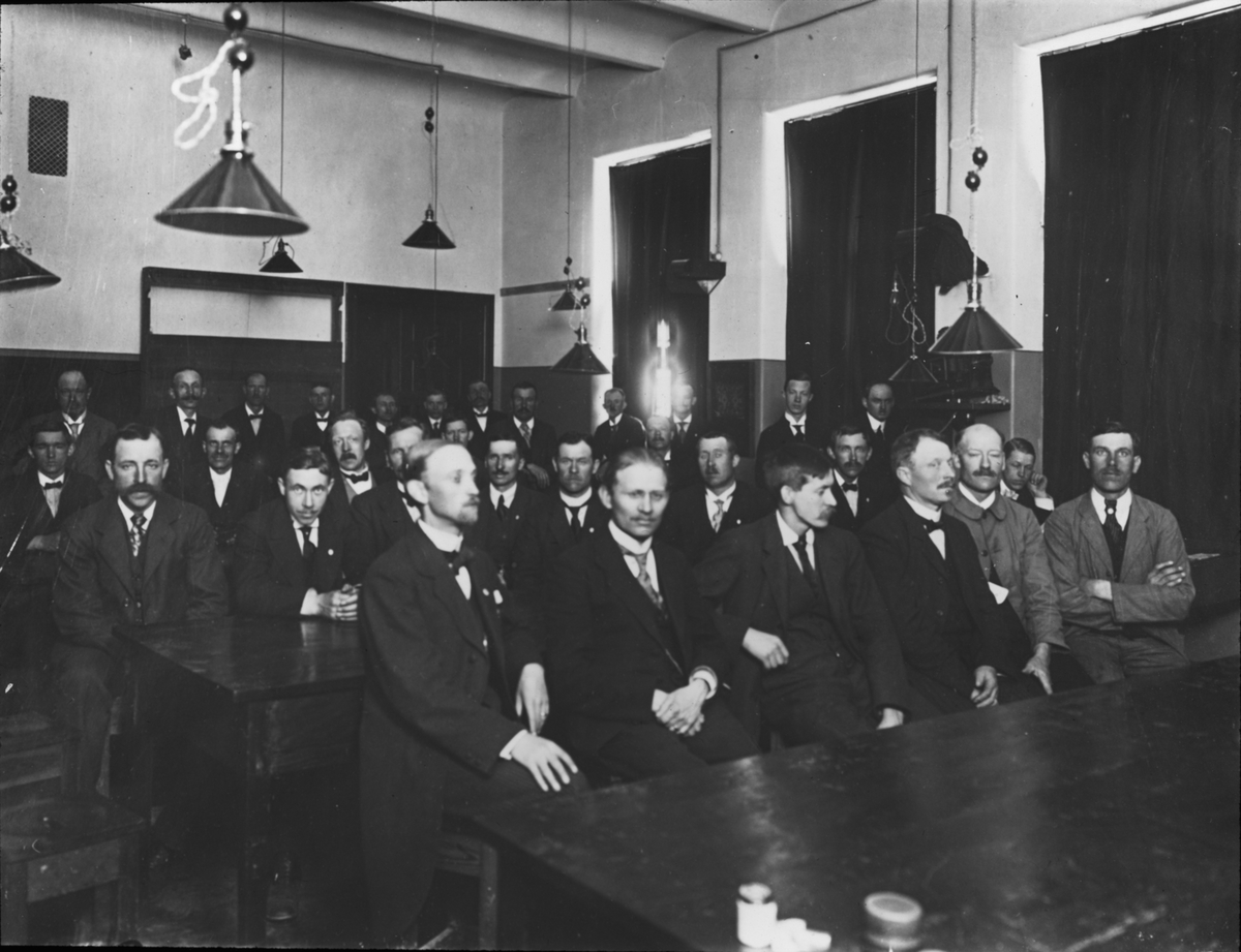 Bild visande skråverksamhet.
Gruppbild av män i lärosal, smeder 1918.