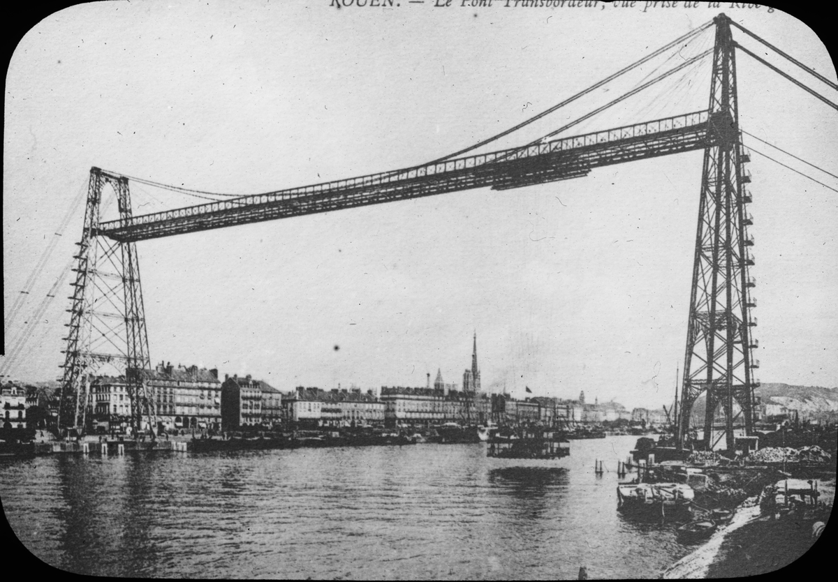 Skioptikonbild med motiv av bron Le Pont Transbordeur i Rouen. Bron byggdes  1899 och stod fram till 1940 då den bombades av franska trupper tyska armén.
Bilden har förvarats i kartong märkt: Resan 1908. Rouen 7. II. Text på bild: "Le Pont Transbordeur".