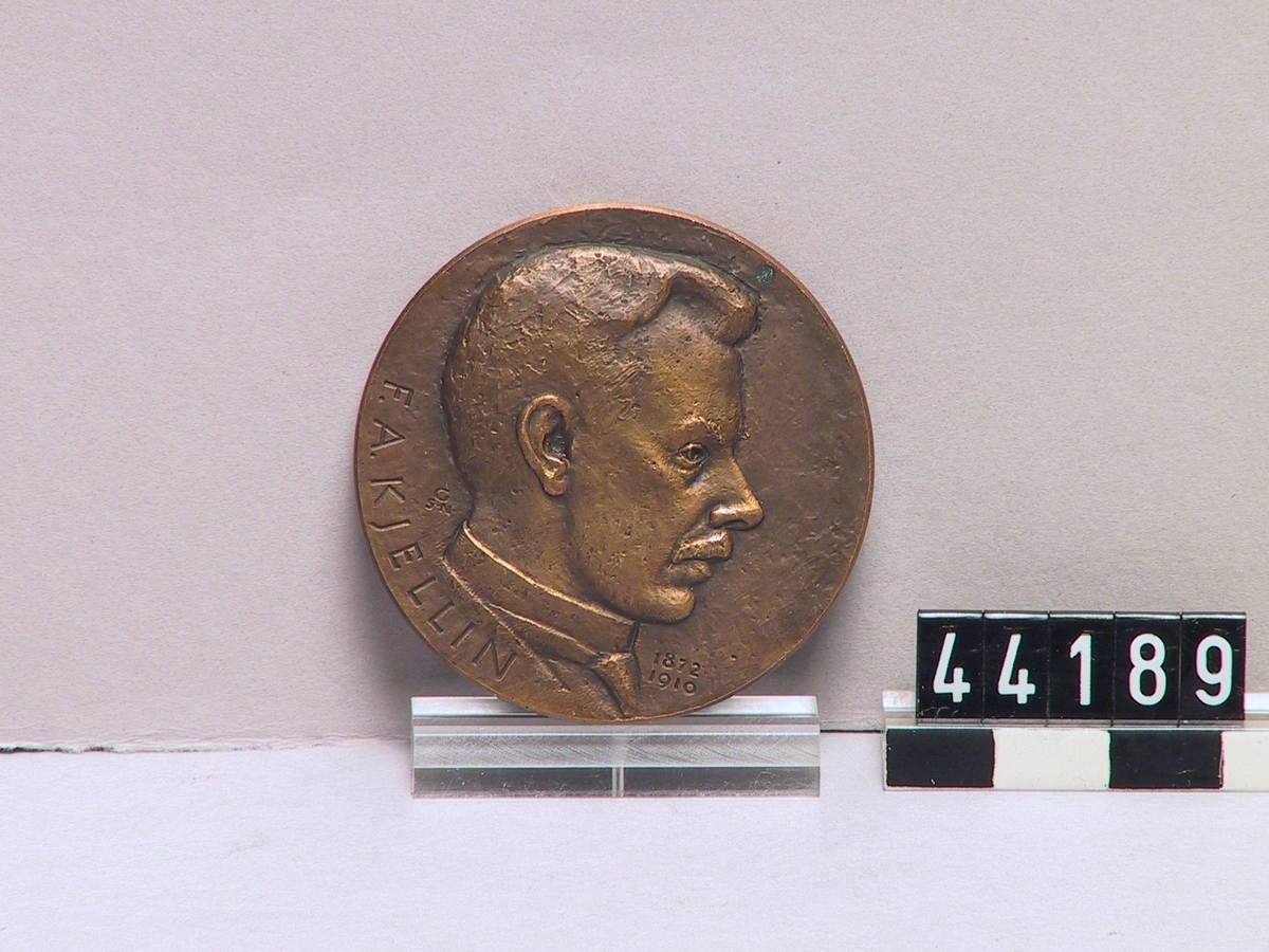 Medalj föreställande F A Kjellin, uppfinnare av elektrostålugnen år 1900. Märkt "Gysinge elektrostål IVA 1974 F.A. Kjellin 1872-1910"