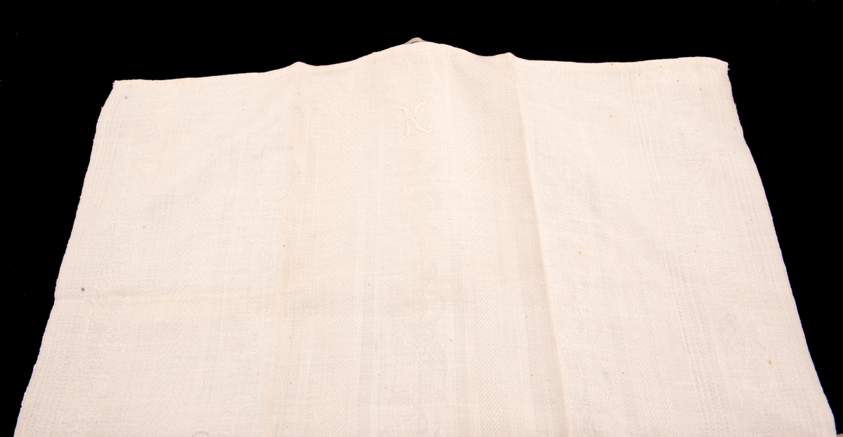Hvitt håndkle med bokstaven K brodert i silkegarn 
