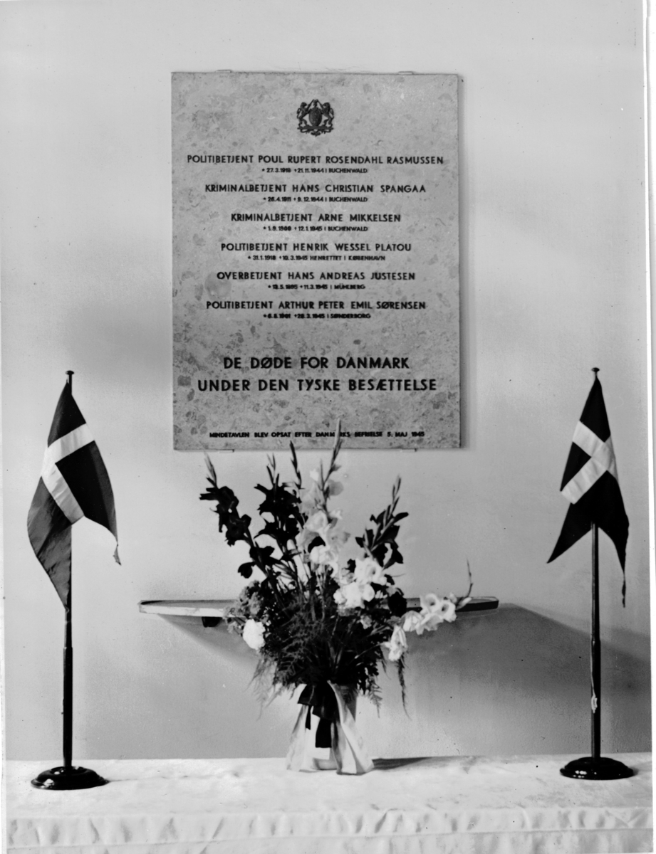 To politimenn står ved minnesmerke for danske politibetjenter som døde under krigen.